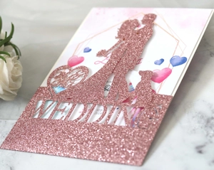 Close-up of rose gold glitter wedding cake topper with couple and dog silhouette design