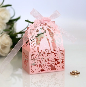 Close-up of pink laser-cut wedding favor box with bride silhouette and silk ribbon