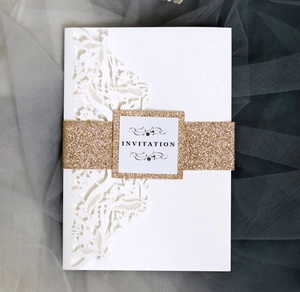 Detailed laser-cut pattern on white business invitation with champagne gold glitter belt