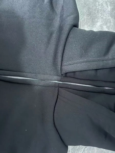 Détail de la fermeture éclair en métal et texture du tricot noir sur le sweat à capuche