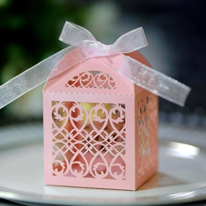 Close-up of pink laser-cut wedding favor box with pearl finish and white ribbon bow