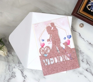 Detail of laser-cut wedding invitation featuring rose gold glitter and kissing couple silhouette
