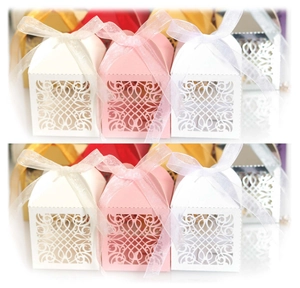 Detail of laser-cut European wedding favor boxes with elegant vine patterns and ribbons