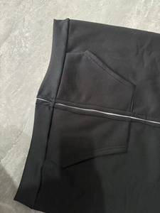 Détail du sweat à capuche noir montrant la taille côtelée, le zip en métal et la poche