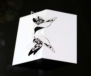 Detailed laser-cut hummingbird seating card with intricate white filigree on black background