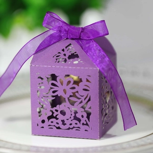 Macro detail of laser-cut purple candy box with floral patterns and silk ribbon bow