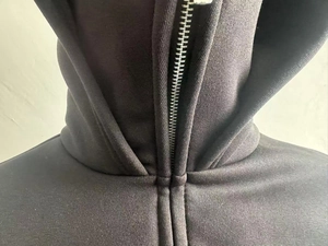 Gros plan d'une fermeture éclair en métal argenté et coutures sur un sweat à capuche noir