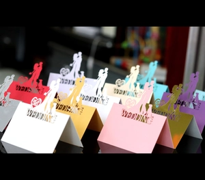 Detail of laser-cut wedding place cards with bride and groom silhouettes in pearl paper