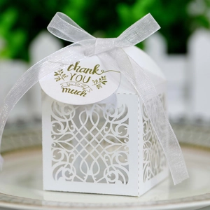 Detail of white laser-cut favor box with silver ribbon and thank you tag for weddings