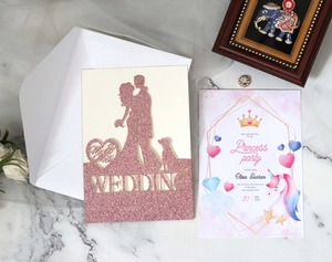 Detail of pink glitter laser cut wedding invitation with couple and dog silhouette
