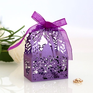 Macro shot of purple laser-cut wedding favor box with ribbon bow and couple silhouette