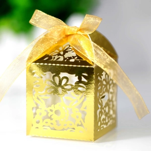 Detail showing the intricate laser-cut floral pattern on golden gift boxes with silk ribbon