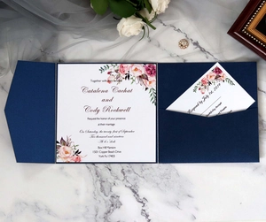 Navy blue laser cut pocket wedding invitation with floral cards on marble background