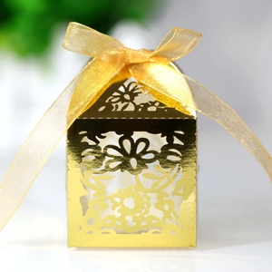 Detail of golden laser-cut wedding favor box with intricate floral hollow pattern
