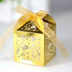 Detailed view of laser-cut gold candy box with intricate floral patterns and ribbon