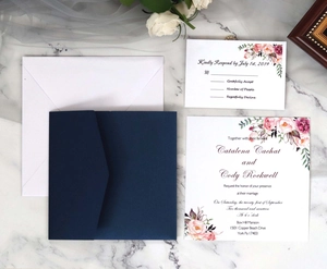 Elegant floral wedding invitation set with navy laser-cut envelope on marble surface