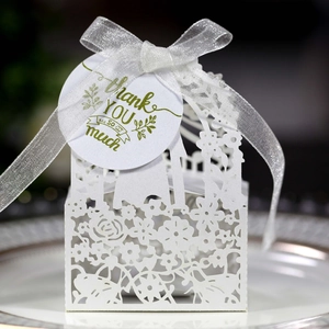 Detailed laser-cut white wedding favor box with floral patterns and a thank you tag