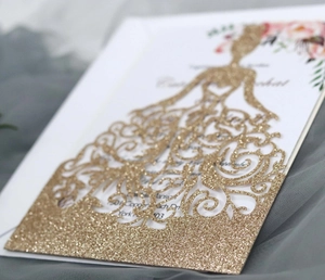 Détail d'invitation de mariage dorée à paillettes avec dentelle de robe découpée au laser