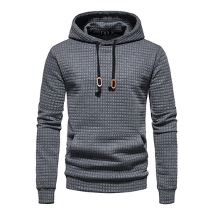 Macro detail of men's grey hoodie featuring 3D waffle texture and kangaroo pocket