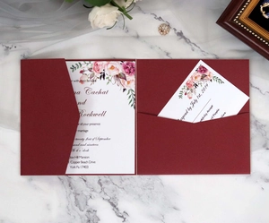 Close-up of burgundy wedding invitation set with floral patterns on marble surface