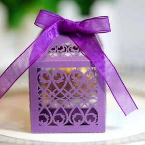 Close-up of purple laser-cut wedding favor box with elegant floral pattern and silk ribbon