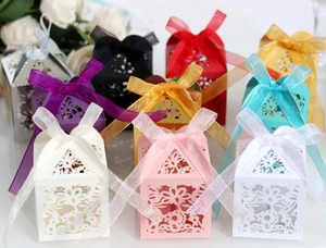 Detail of laser-cut floral wedding favor boxes with elegant organza ribbons in various colors