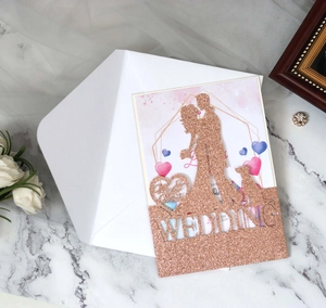 Macro view of rose gold glitter laser-cut wedding invitation with silhouette and envelope