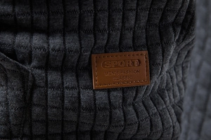 Macro shot of waffle knit fabric and brown leather label on a men's grey hoodie