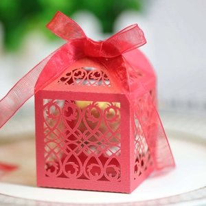 Close-up of red laser-cut wedding gift box with heart hollow patterns and a silk ribbon
