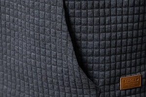 Macro view of dark grey quilted waffle fabric with decorative brown leather sport label