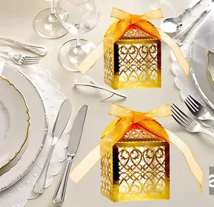 Laser-cut hollow gold wedding favor box with intricate heart patterns and orange ribbon