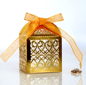 Detail of laser-cut gold candy box with intricate floral patterns and silk ribbon bow