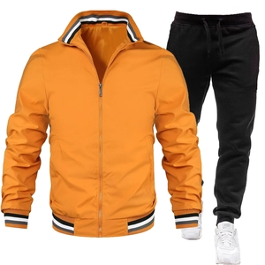Detail der gelben Reißverschlussjacke mit gestreiften Rippbündchen und schwarzer Jogginghose