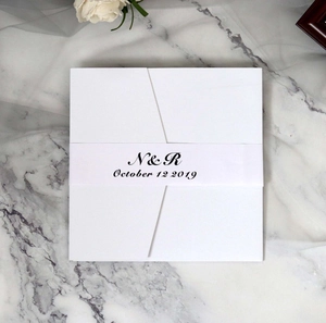 Detailed view of a square white laser-cut wedding invitation with custom paper belly band