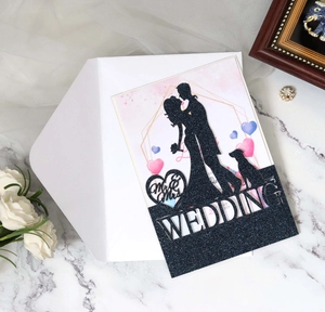 Macro shot of glitter black wedding invitation featuring laser cut couple silhouette