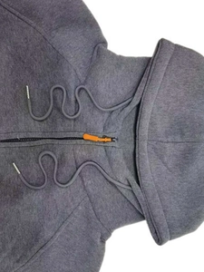 Détail d'un sweat à capuche gris avec fermeture éclair orange et cordons ondulés