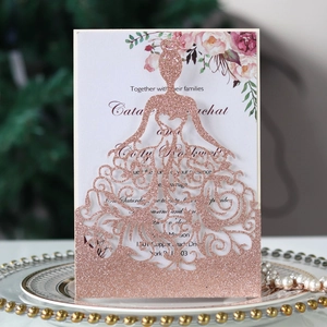 Détail d'invitation de mariage en paillettes or rose découpée au laser en robe