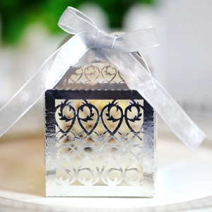 Macro detail of laser-cut silver favor box with hollow heart patterns and satin ribbon