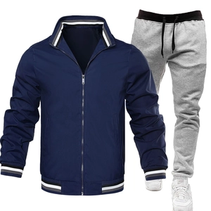 Detail der marineblauen Windjacke mit gestreiften Rippbündchen und grauer Jogginghose