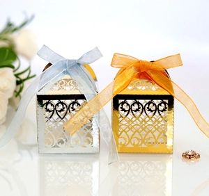 Macro detail of laser-cut wedding favor box with shiny gold finish and satin ribbon