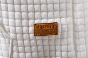 Detail of white waffle quilted fabric featuring a brown embossed faux leather patch