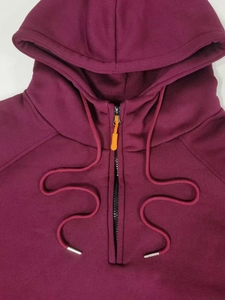 Détail du sweat à capuche bordeaux avec fermeture éclair orange et cordons de serrage
