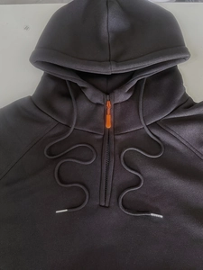 Détail d'un sweat à capuche noir avec tissu haute densité et zip orange vif