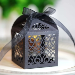 Detail of laser-cut matte black wedding candy box with vine patterns and silk ribbon bow