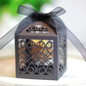Detail of laser-cut European scroll patterns on a black wedding candy box with a silk bow