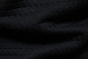 Macro view of black waffle knit textured fabric showing detailed grid weaving pattern