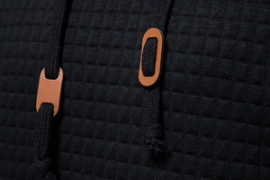Detail view of black waffle knit texture with drawstring and brown leather toggle on hoodie