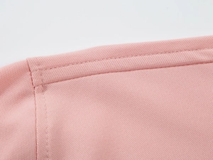 Gros plan détaillé de la couture d'épaule d'un polo rose avec finition double piqûre