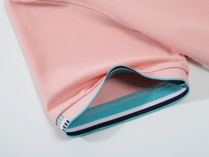 Macro d'un poignet de polo rose clair avec côtes rayées et tissu en maille piquée
