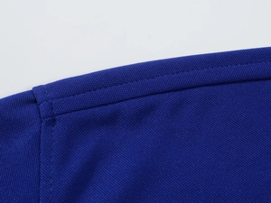 Macro shot of royal blue pique polo shirt fabric showing breathable texture and stitching